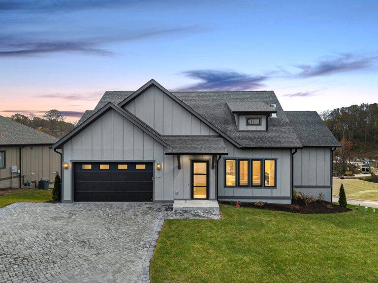 Modern farmhouse-style custom home exterior with warm gray board-and-batten siding at dusk, built by Big Hills Construction in Asheville, NC
