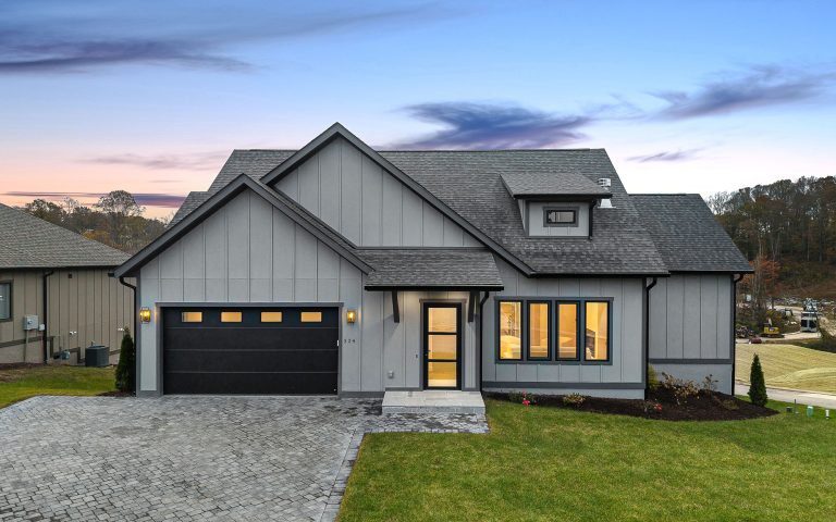 Modern farmhouse-style custom home exterior with warm gray board-and-batten siding at dusk, built by Big Hills Construction in Asheville, NC